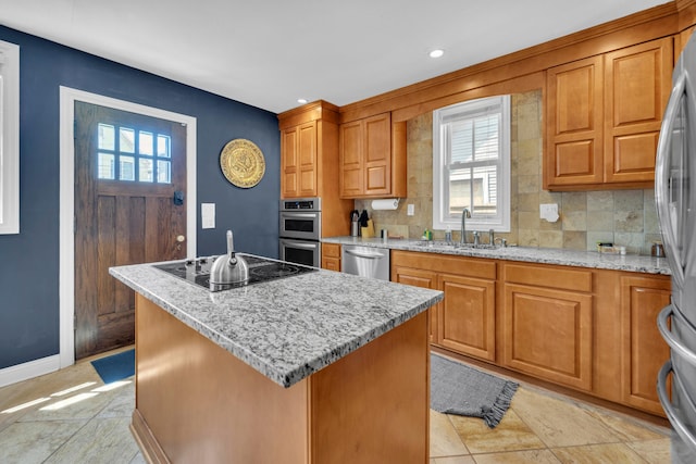 609 Mohawk St, Columbus, OH 43206 - kitchen featuring a sink, stainless steel appliances, a kitchen island, light stone countertops, and brown cabinetry