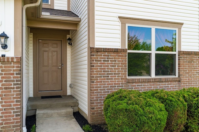view of exterior entry featuring brick siding