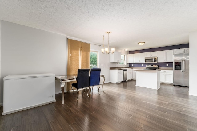 kitchen with stainless steel appliances, a chandelier, dark wood-type flooring, white cabinets, and a textured ceiling