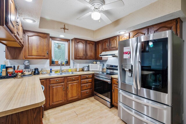 214 Sylvan Dr, Delaware, OH 43015 - kitchen with appliances with stainless steel finishes, a sink, under cabinet range hood, light wood finished floors, and a textured ceiling