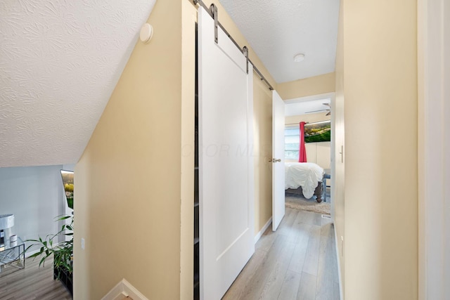 5309 Trillium Ct, Columbus, OH 43230 - hall featuring a barn door, light wood-style floors, baseboards, and a textured ceiling
