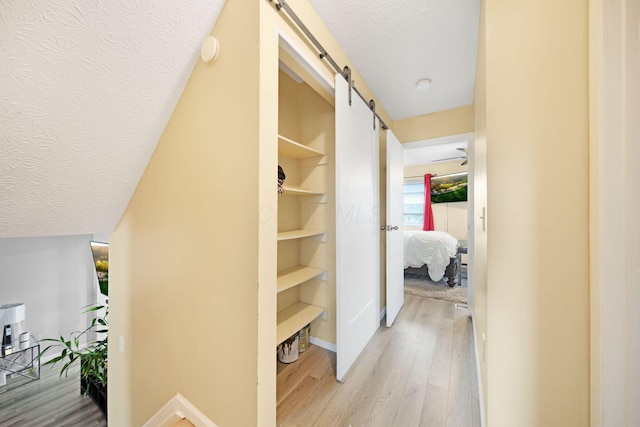 5309 Trillium Ct, Columbus, OH 43230 - corridor with a barn door, light wood-type flooring, a textured ceiling, baseboards, and built in shelves