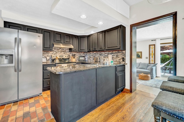 606 S 9th St, Columbus, OH 43206 - kitchen with appliances with stainless steel finishes, backsplash, a peninsula, under cabinet range hood, and dark stone counters