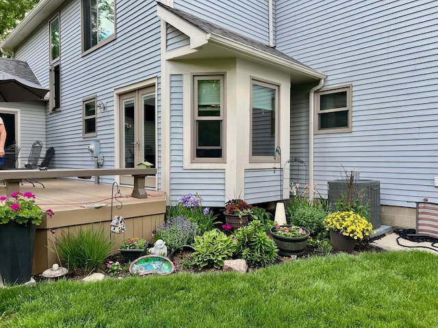 view of side of home with central AC unit, a wooden deck, french doors, and a yard