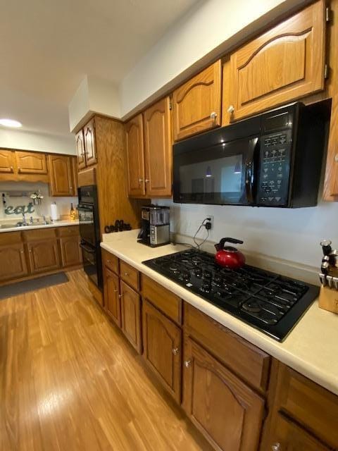 281 Bexford Rd, West Jefferson, OH 43162 - kitchen featuring black appliances, brown cabinetry, a sink, light countertops, and light wood-style flooring