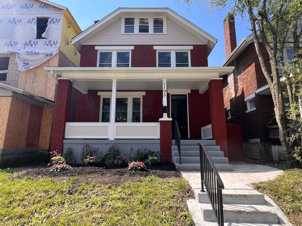 traditional style home featuring covered porch and brick siding