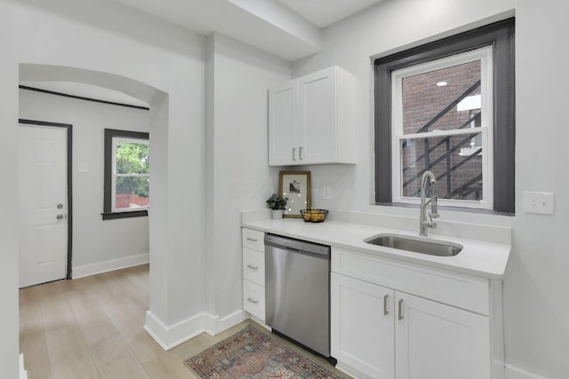 1195 E Whittier St, Columbus, OH 43206 - kitchen with stainless steel dishwasher, a sink, light countertops, white cabinets, and baseboards