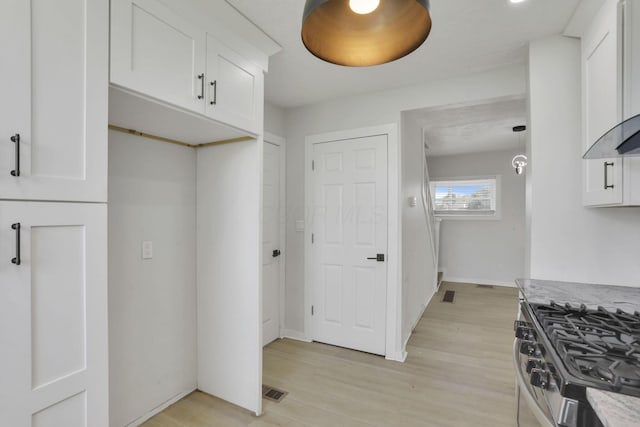 841 Saint Clair Ave, Columbus, OH 43201 - kitchen with gas range, white cabinets, light wood-type flooring, and wall chimney range hood