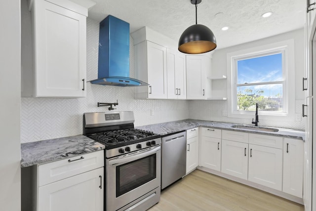 841 Saint Clair Ave, Columbus, OH 43201 - kitchen featuring appliances with stainless steel finishes, wall chimney exhaust hood, a sink, white cabinetry, and decorative backsplash