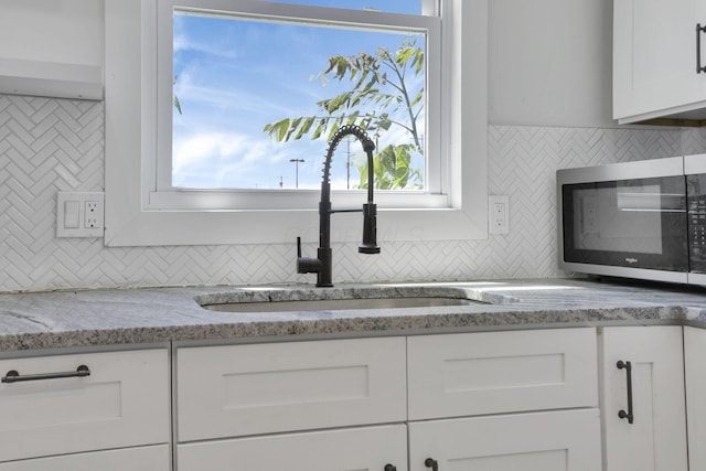 841 Saint Clair Ave, Columbus, OH 43201 - kitchen with stainless steel microwave, a sink, tasteful backsplash, and white cabinetry