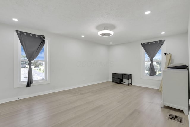 841 Saint Clair Ave, Columbus, OH 43201 - unfurnished living room with light wood-type flooring, healthy amount of natural light, recessed lighting, baseboards, and a textured ceiling