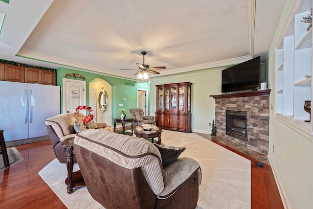 7563 Jenkins Dr, Canal Winchester, OH 43110 - living room with a stone fireplace, light wood-style flooring, a ceiling fan, baseboards, and ornamental molding