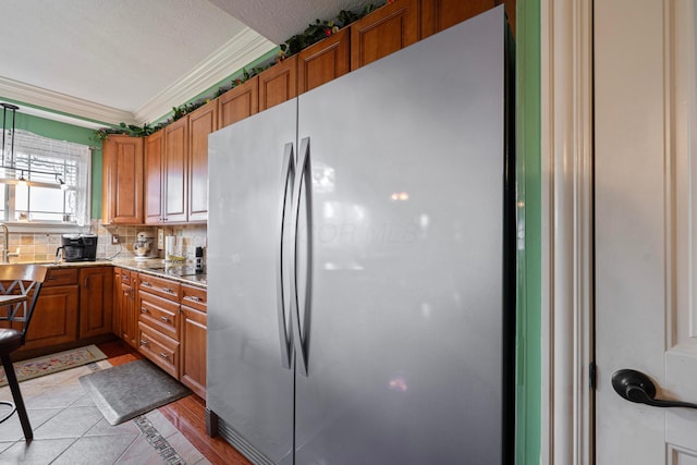 7563 Jenkins Dr, Canal Winchester, OH 43110 - kitchen with freestanding refrigerator, brown cabinets, ornamental molding, light countertops, and decorative backsplash