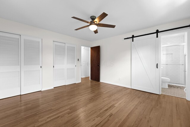 270 S Kellner Rd, Columbus, OH 43209 - unfurnished bedroom featuring multiple closets, a barn door, wood finished floors, ensuite bathroom, and baseboards