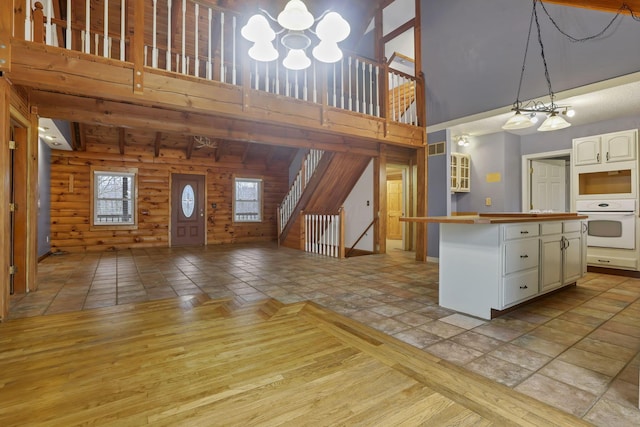 7760 Township Rd 177, Fredericktown, OH 43019 - kitchen with a chandelier, a towering ceiling, white oven, open floor plan, and white cabinetry