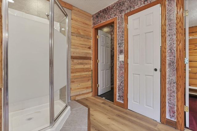 7760 Township Rd 177, Fredericktown, OH 43019 - full bathroom featuring a stall shower, wood finished floors, wallpapered walls, and wood walls