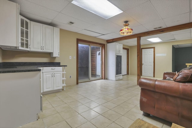 7760 Township Rd 177, Fredericktown, OH 43019 - kitchen featuring a paneled ceiling, white cabinets, dark countertops, glass insert cabinets, and light tile patterned floors