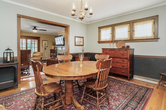 2454 Seneca Park Pl, Columbus, OH 43209 - dining room with light wood finished floors, crown molding, a ceiling fan, and a chandelier