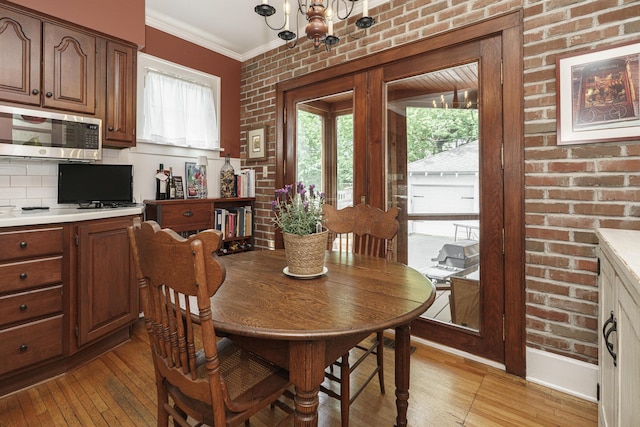 2454 Seneca Park Pl, Columbus, OH 43209 - dining space featuring a chandelier, light wood-style flooring, crown molding, and brick wall