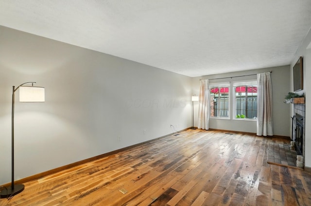 127 Saint Michelle St Unit 35B, Columbus, OH 43085 - unfurnished living room featuring hardwood / wood-style flooring, baseboards, and a fireplace with raised hearth