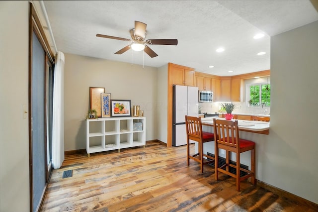127 Saint Michelle St Unit 35B, Columbus, OH 43085 - kitchen featuring stainless steel microwave, freestanding refrigerator, recessed lighting, light wood-style floors, and ceiling fan