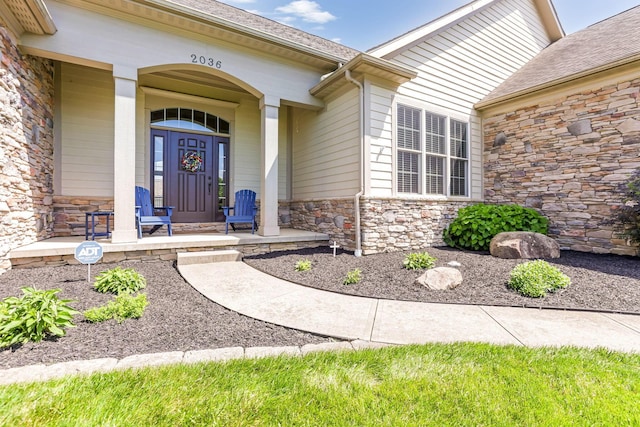 2036 Amber Wood Pl, Lancaster, OH 43130 - view of exterior entry with stone siding, a porch, and roof with shingles