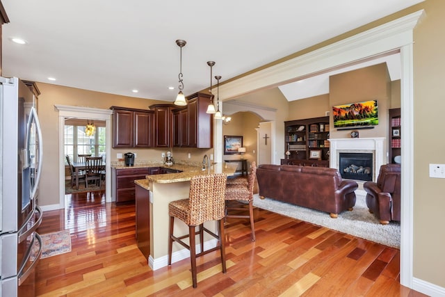 2036 Amber Wood Pl, Lancaster, OH 43130 - kitchen featuring stainless steel fridge with ice dispenser, a breakfast bar area, light wood finished floors, a peninsula, and dark brown cabinets