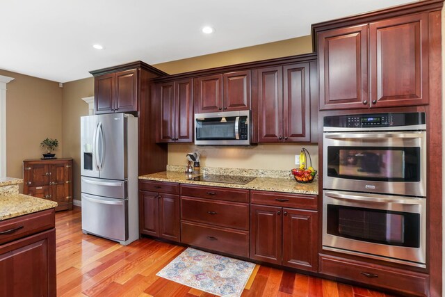 2036 Amber Wood Pl, Lancaster, OH 43130 - kitchen with appliances with stainless steel finishes, light wood finished floors, light stone countertops, reddish brown cabinets, and recessed lighting