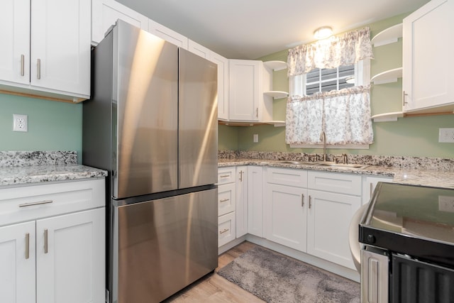 162 E Morrill Ave, Columbus, OH 43207 - kitchen with freestanding refrigerator, open shelves, a sink, white cabinets, and light wood-type flooring