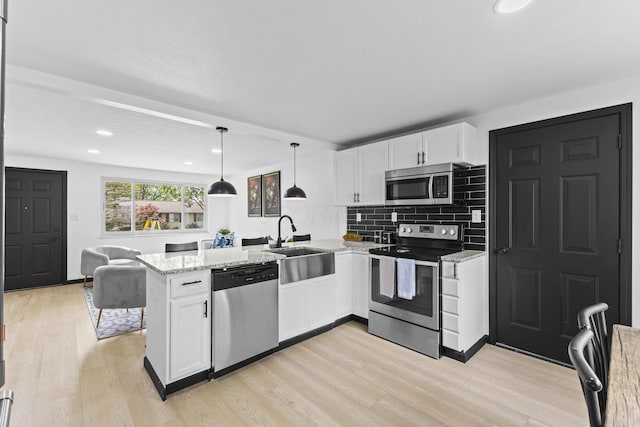 1530 Lexdale Dr, Reynoldsburg, OH 43068 - kitchen with appliances with stainless steel finishes, a sink, white cabinetry, a peninsula, and recessed lighting