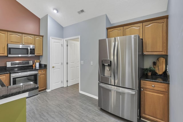 6542 Lakeview Cir, Canal Winchester, OH 43110 - kitchen with stainless steel appliances, dark stone counters, vaulted ceiling, light wood-style flooring, and a textured ceiling