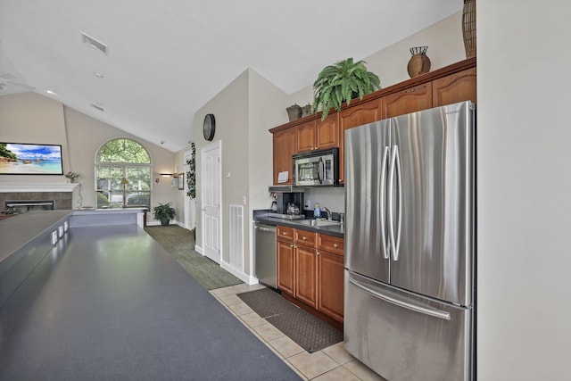 6542 Lakeview Cir, Canal Winchester, OH 43110 - kitchen featuring appliances with stainless steel finishes, lofted ceiling, a tile fireplace, dark countertops, and brown cabinets