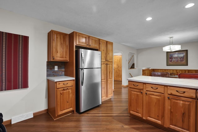 699 Cedar Run Rd NE, Newark, OH 43055 - kitchen featuring freestanding refrigerator, arched walkways, dark wood-style floors, light countertops, and brown cabinetry