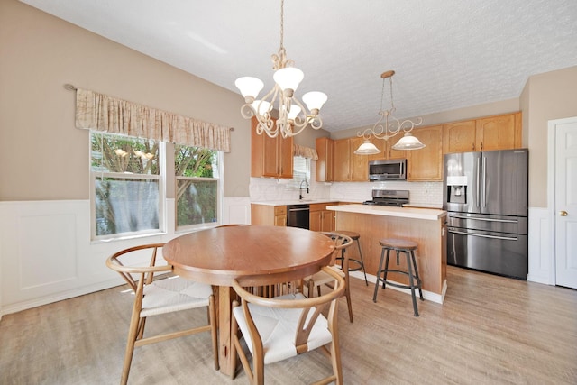 272 Trail E, Etna, OH 43062 - dining space featuring light wood finished floors, a chandelier, wainscoting, and a textured ceiling