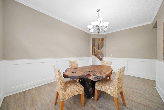 272 Trail E, Etna, OH 43062 - dining space with a chandelier, stairs, a wainscoted wall, light wood finished floors, and ornamental molding