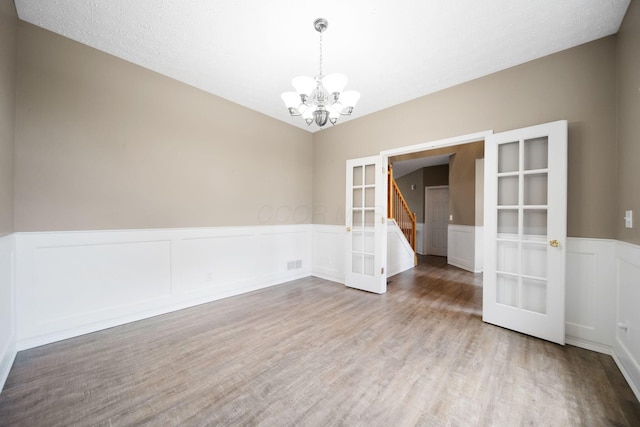 272 Trail E, Etna, OH 43062 - empty room with french doors, a chandelier, a wainscoted wall, light wood-style flooring, and a decorative wall