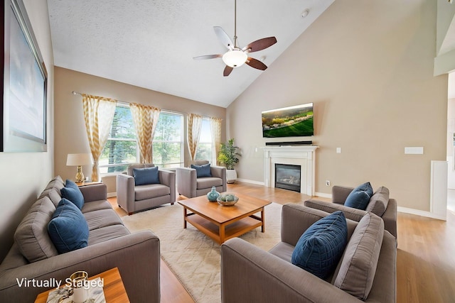 272 Trail E, Etna, OH 43062 - living room featuring a glass covered fireplace, a ceiling fan, high vaulted ceiling, light wood-type flooring, and baseboards