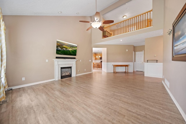 272 Trail E, Etna, OH 43062 - unfurnished living room featuring high vaulted ceiling, ceiling fan, wood finished floors, a glass covered fireplace, and baseboards