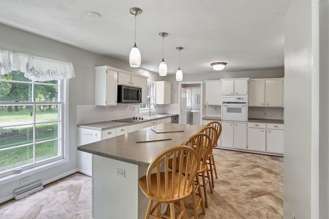 498 Manor, Newark, OH 43055 - kitchen with black appliances, white cabinets, backsplash, hanging light fixtures, and a breakfast bar