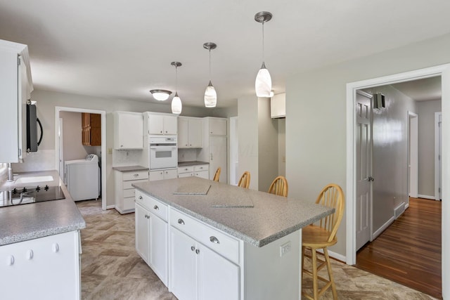 498 Manor, Newark, OH 43055 - kitchen with black appliances, a kitchen island, a breakfast bar, white cabinets, and decorative light fixtures