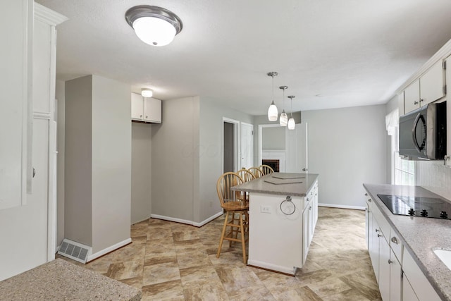 498 Manor, Newark, OH 43055 - kitchen with black appliances, white cabinetry, a breakfast bar, a kitchen island, and baseboards