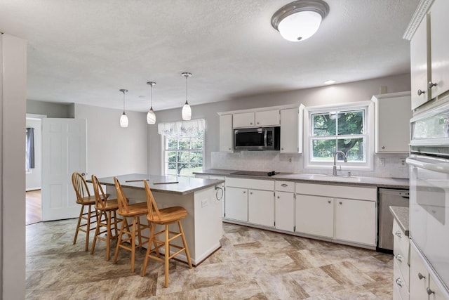 498 Manor, Newark, OH 43055 - kitchen featuring appliances with stainless steel finishes, a sink, tasteful backsplash, a kitchen bar, and a textured ceiling