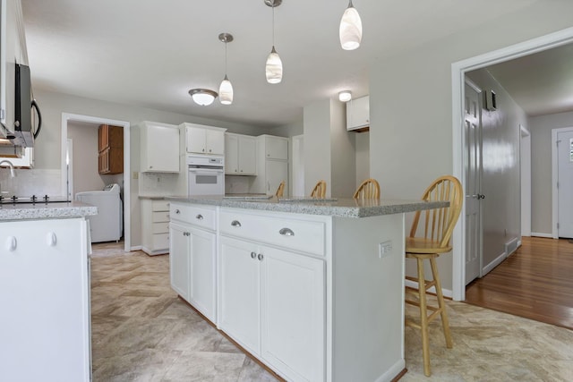 498 Manor, Newark, OH 43055 - kitchen with white oven, white cabinetry, decorative light fixtures, a kitchen island, and backsplash