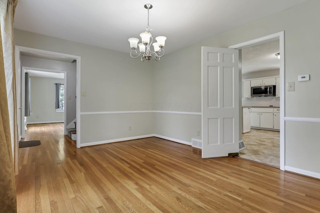 498 Manor, Newark, OH 43055 - spare room with light wood-style floors, a chandelier, baseboards, and stairs