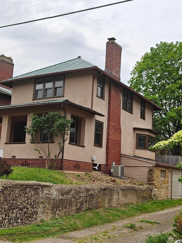 16 N 7th St, Newark, OH 43055 - view of property exterior featuring a chimney, central air condition unit, stucco siding, and metal roof