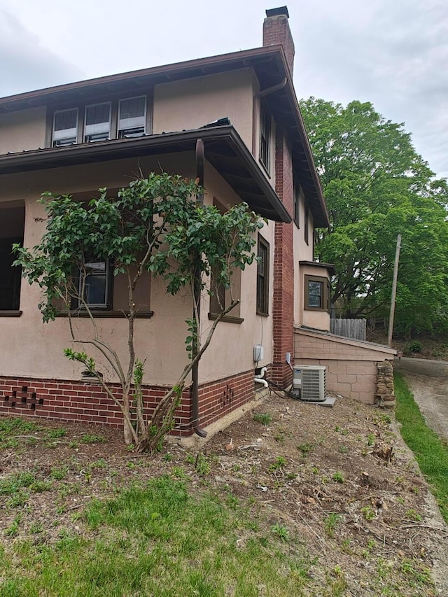 16 N 7th St, Newark, OH 43055 - view of side of home featuring stucco siding, central AC unit, brick siding, and a chimney