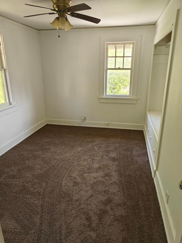 16 N 7th St, Newark, OH 43055 - unfurnished bedroom with multiple windows, dark carpet, crown molding, ceiling fan, and baseboards