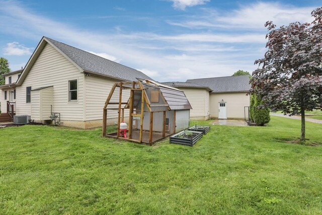 8270 Windy Hollow Rd, Johnstown, OH 43031 - rear view of house featuring a yard, a shingled roof, an outbuilding, central AC unit, and a garden
