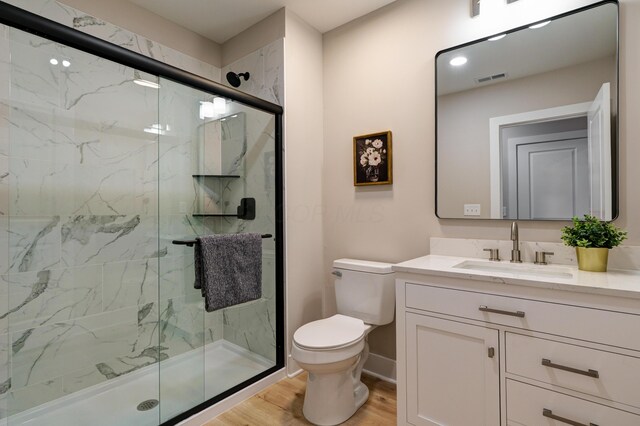 2587 Dayton Ave, Columbus, OH 43202 - full bathroom with toilet, wood finished floors, vanity, and a marble finish shower