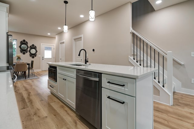 2587 Dayton Ave, Columbus, OH 43202 - kitchen with stainless steel dishwasher, a sink, built in microwave, light wood-style floors, and decorative light fixtures